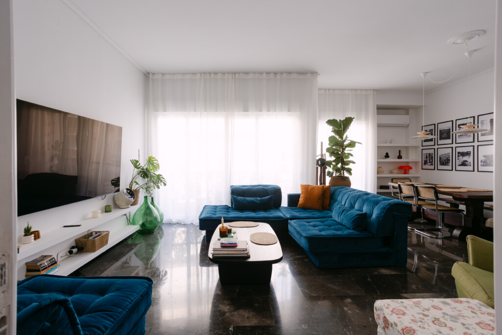 Living room with blue velvet sofa, Smart TV and large windows