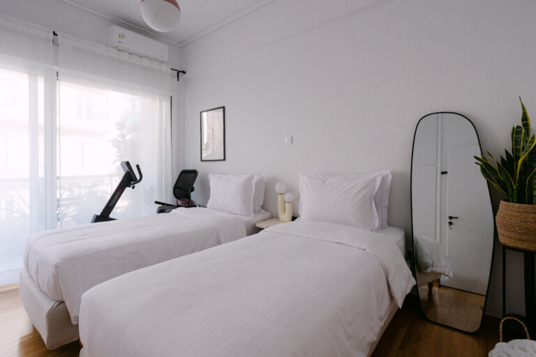 Bright twin bedroom with two single beds and floor-to-ceiling windows