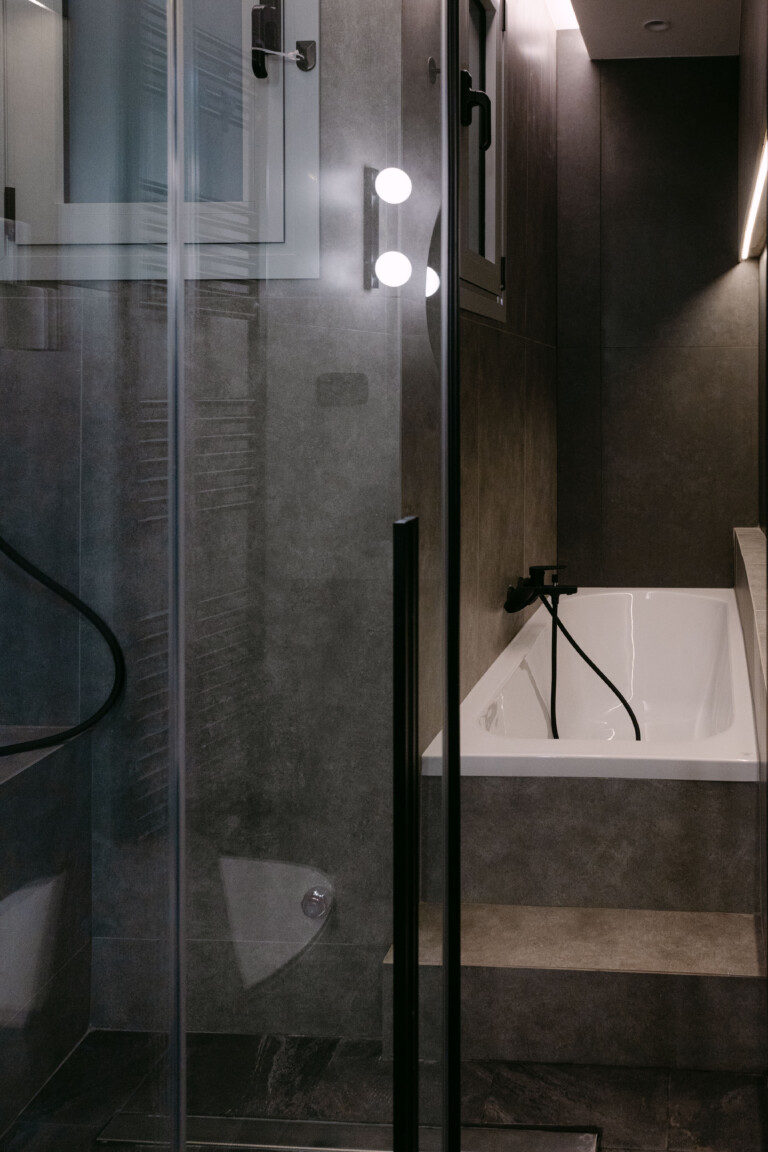 Modern dark-tiled bathroom with bathtub