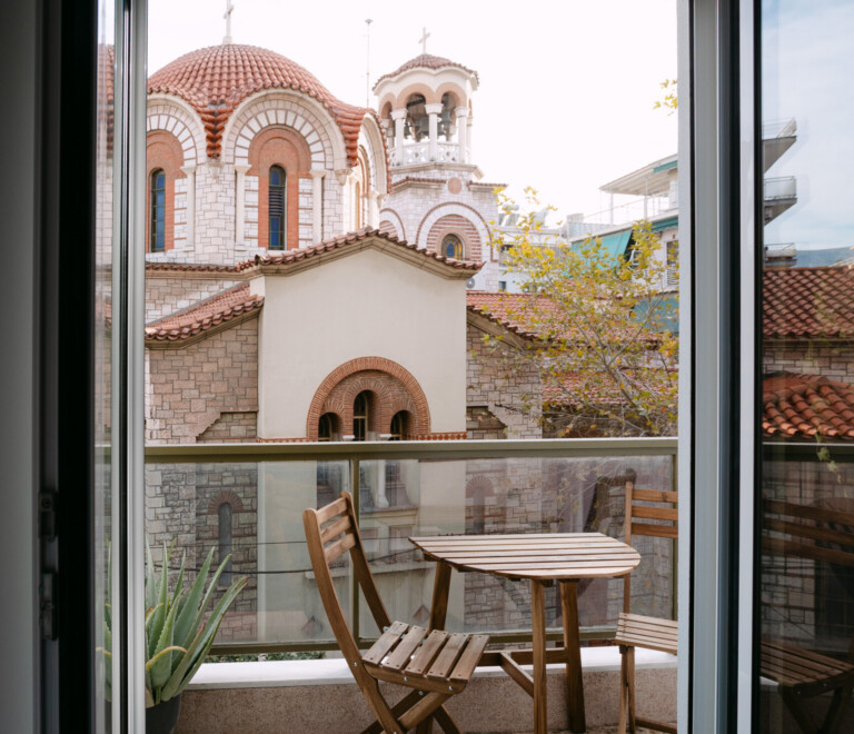 Balcony with café table and chairs overlooking a Byzantine church in Koukaki, Athens