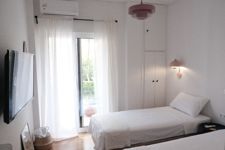 Bright single bedroom with sheer curtains and balcony door